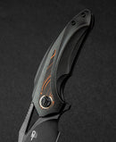 Bestech Nuke BT2107E handle detail – black G10 and orange G10 inlay texture on titanium
