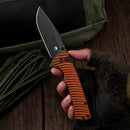 Klaken J392 Riftline J392-OrangeG10-BlackBlade held in hand showing orange G10 handle and black D2 blade